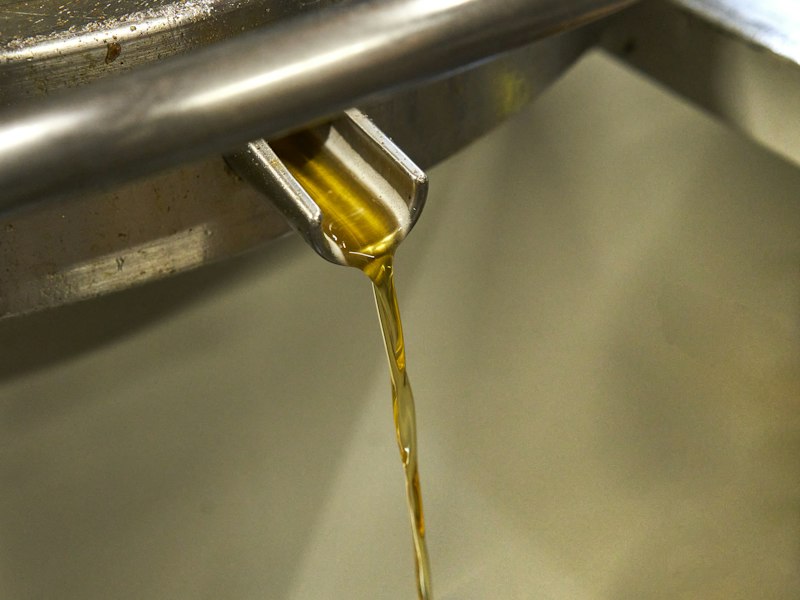 Golden cooking oil pouring from a steel spout
